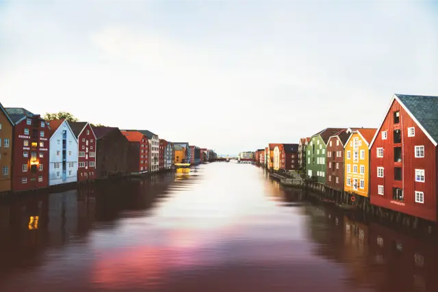 Painted wooden warehouses along a calm river in Trondheim, in Agfa Vista 400