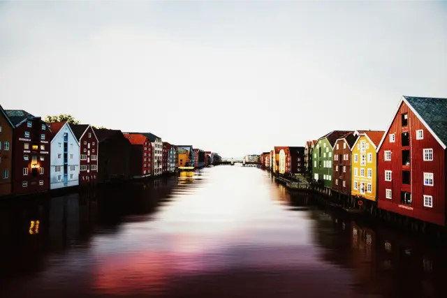 Painted wooden warehouses along a calm river in Trondheim, in VNTG 800