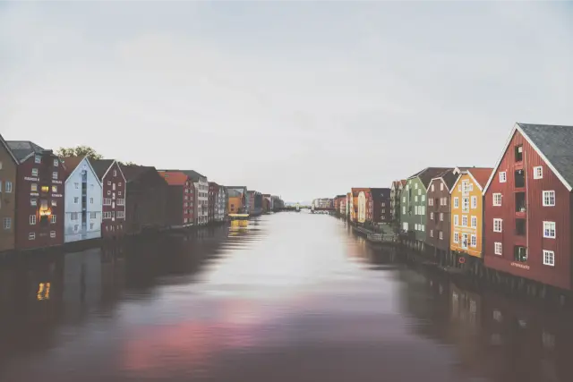 Painted wooden warehouses along a calm river in Trondheim, in Fuji Pro 400H