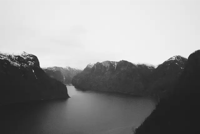 A dark blue fjord between snow-topped mountains, in Ilford Delta 3200