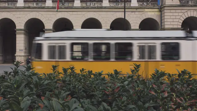 A yellow tram passing a stone arcade in Budapest, in Kodak Portra 800