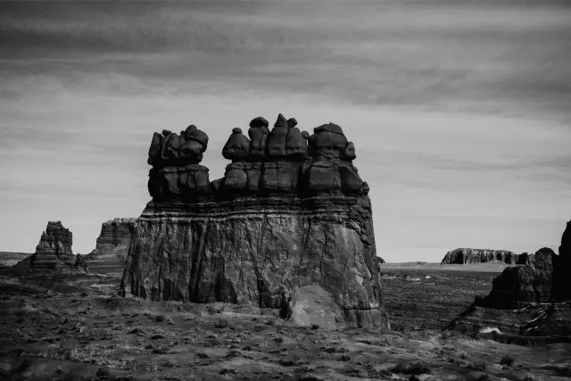 A red sandstone formation under a pale blue desert sky, in MONO X 400