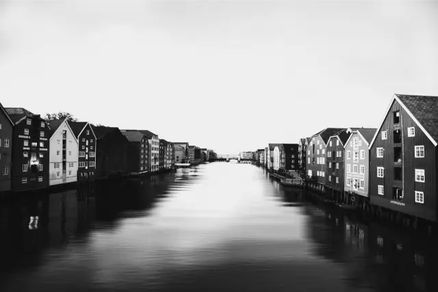 Painted wooden warehouses along a calm river in Trondheim, in MONO X 400