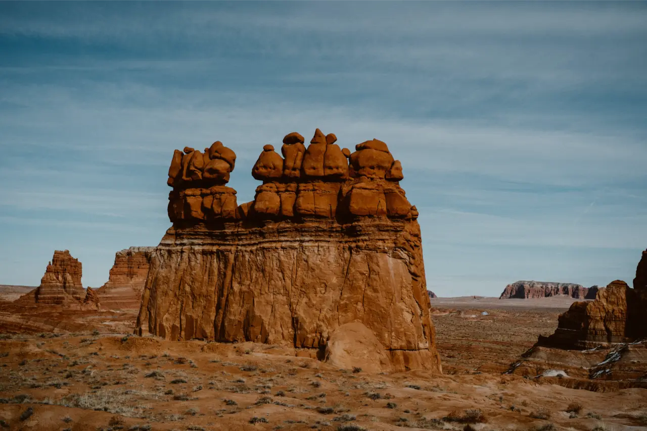 A red sandstone formation under a pale blue desert sky, unedited