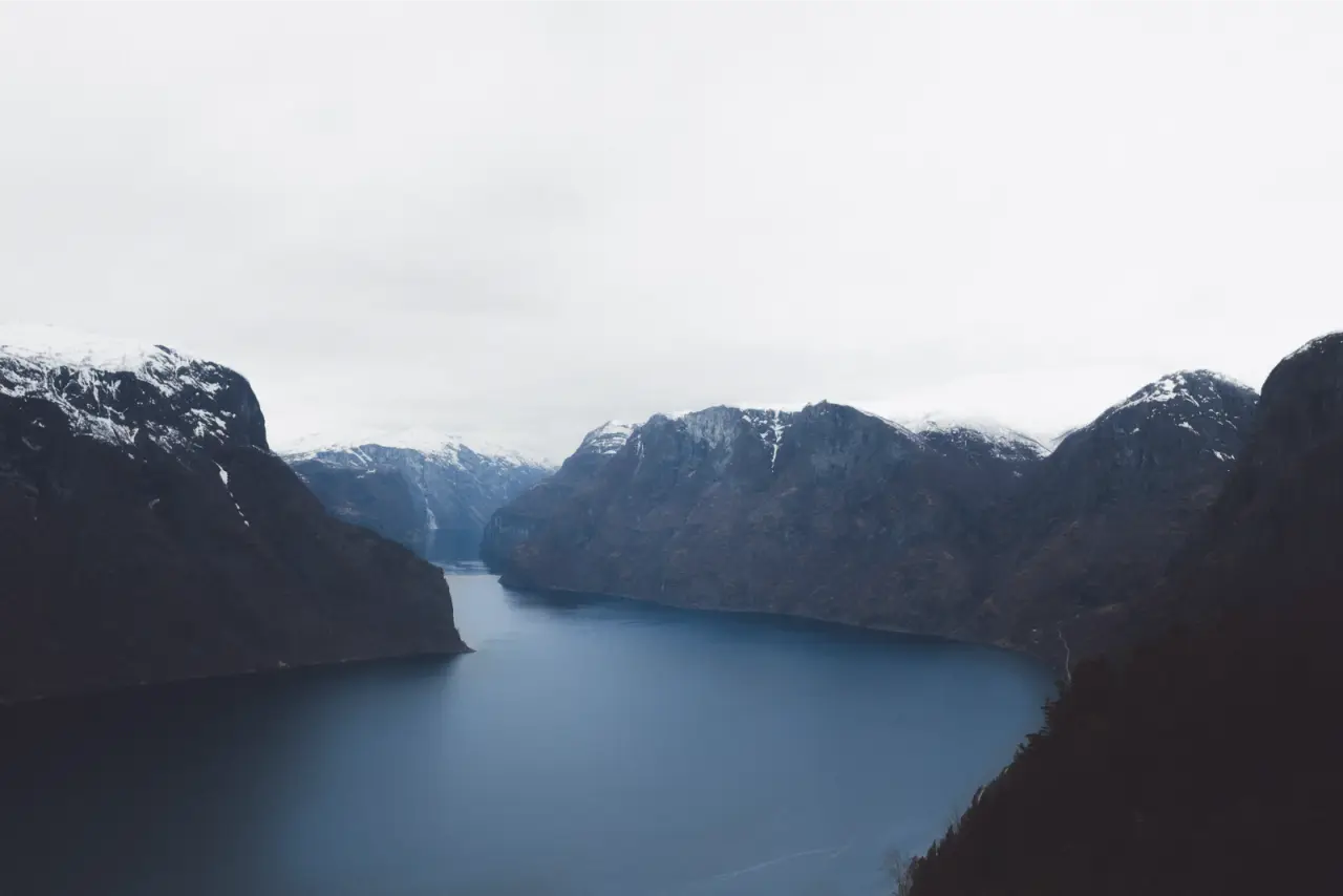 A dark blue fjord between snow-topped mountains, unedited