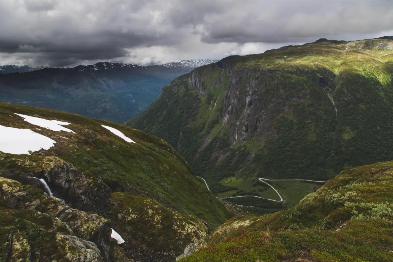 A green mountain valley with patches of snow under heavy cloud, unedited