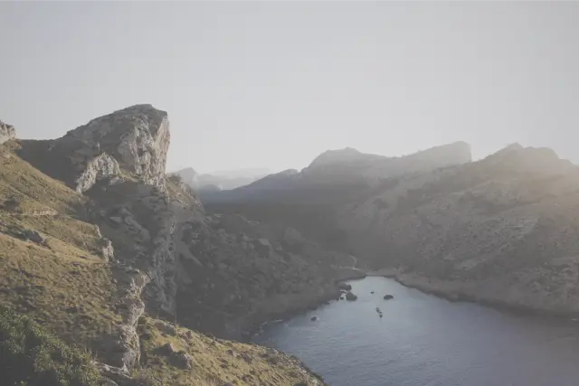 Sunlit cliffs above a narrow bay on Mallorca, in Polaroid 600