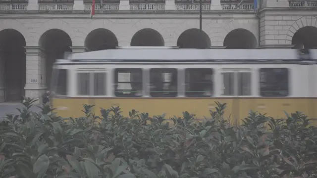 A yellow tram passing a stone arcade in Budapest, in Polaroid 600