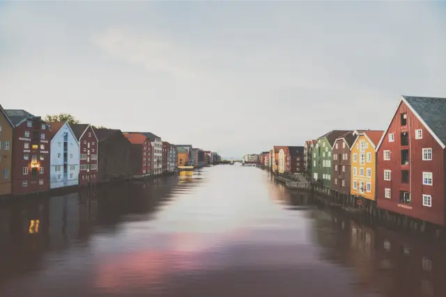 Painted wooden warehouses along a calm river in Trondheim, in VNTG F 160