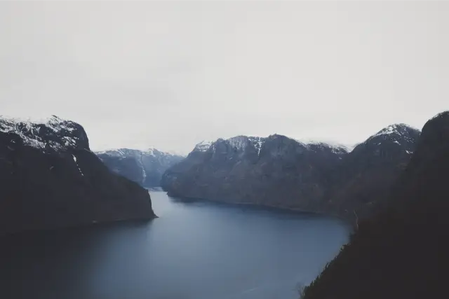 A dark blue fjord between snow-topped mountains, in Pro Neg Hi