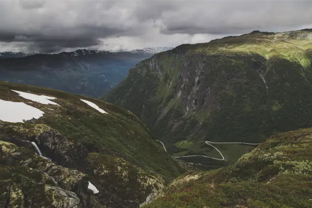 A green mountain valley with patches of snow under heavy cloud, in Pro Neg Hi