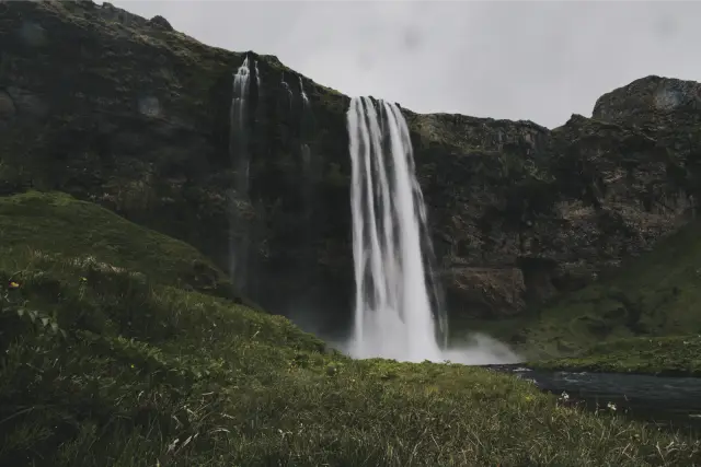 A tall waterfall dropping over a green cliff in Iceland, in Pro Neg Hi