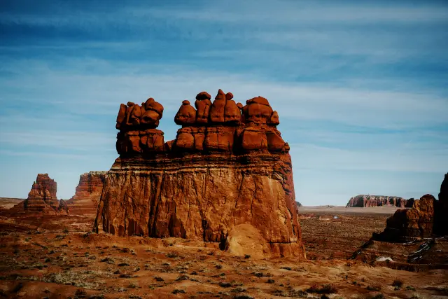 A red sandstone formation under a pale blue desert sky, in NEO v 90